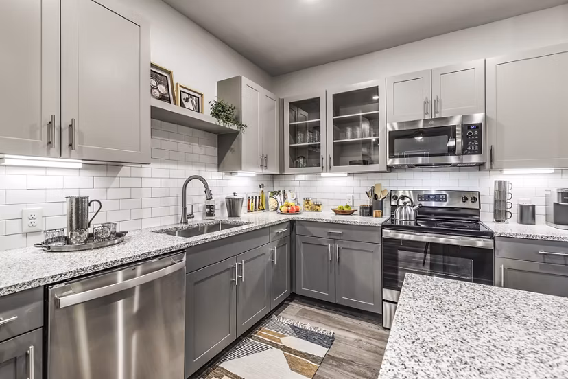 Modern kitchen with stainless steel appliances and granite countertops in Arista Riverstone Apartments