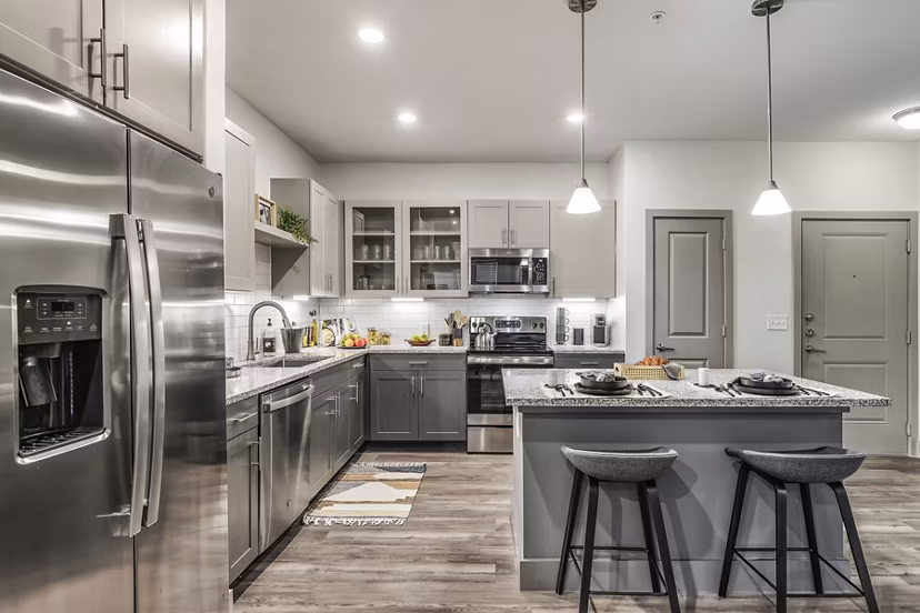 Modern kitchen with stainless steel appliances and granite countertops at Arista Riverstone Apartments