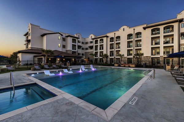 Poolside retreat at Arista Riverstone Apartments featuring a luxurious pool surrounded by landscaped gardens