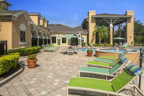 Poolside patio with modern chairs and lush greenery at The Lofts Apartments, offering luxury outdoor relaxation space