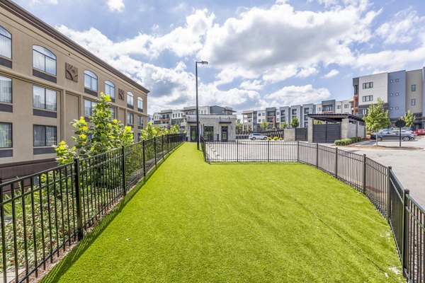 Fenced dog park with agility equipment at Candour House Apartments