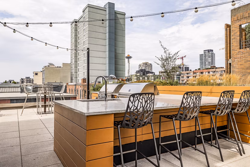 Outdoor patio with grill area at Elara at the Market Apartments featuring comfortable seating for social gatherings