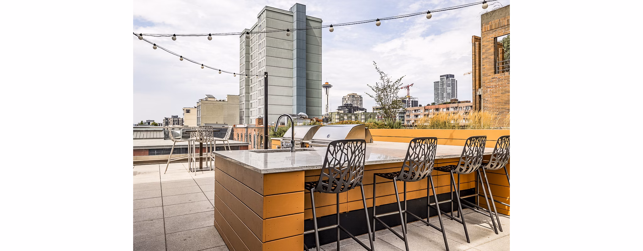 Outdoor patio with grill area at Elara at the Market Apartments featuring comfortable seating for social gatherings