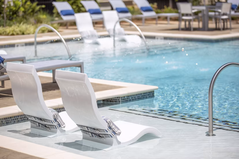 Resort-style pool at Newbergh ATL Apartments, featuring lush landscaping and sun deck areas
