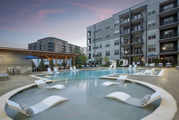 Luxurious outdoor pool area at Newbergh ATL Apartments with lounge seating and city skyline views