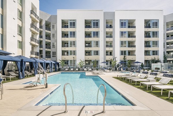 Luxurious pool at Parallel Apartments with lounge chairs and palm trees, offering a tranquil outdoor space for residents to relax and unwind
