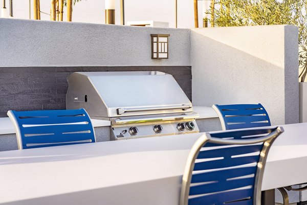 Outdoor grill area surrounded by greenery at Parallel Apartments, ideal for social gatherings and BBQs