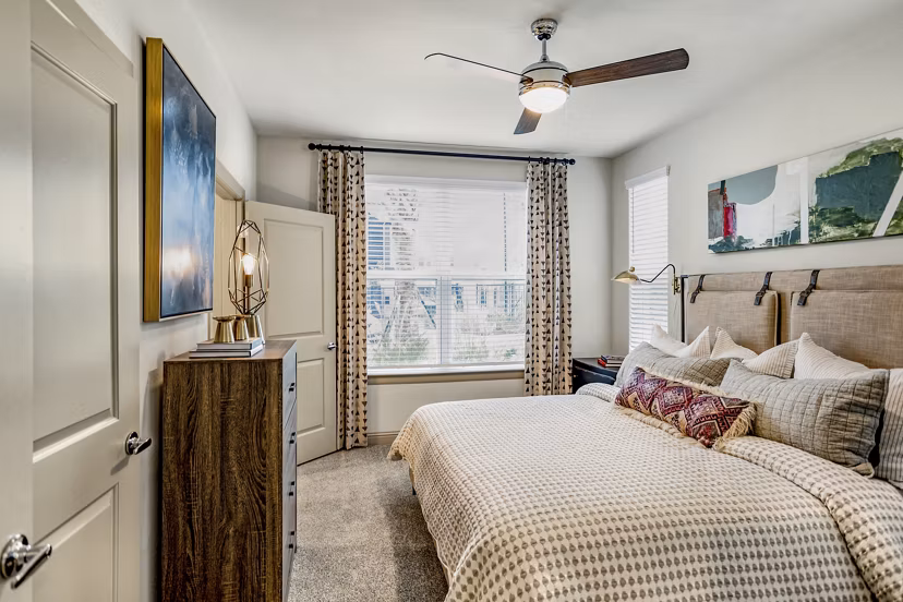 Cozy bedroom featuring modern decor and large windows in Domain Town Center Apartments