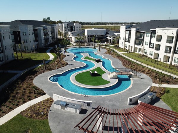 Luxury apartment complex featuring a large winding swimming pool surrounded by lush landscaping