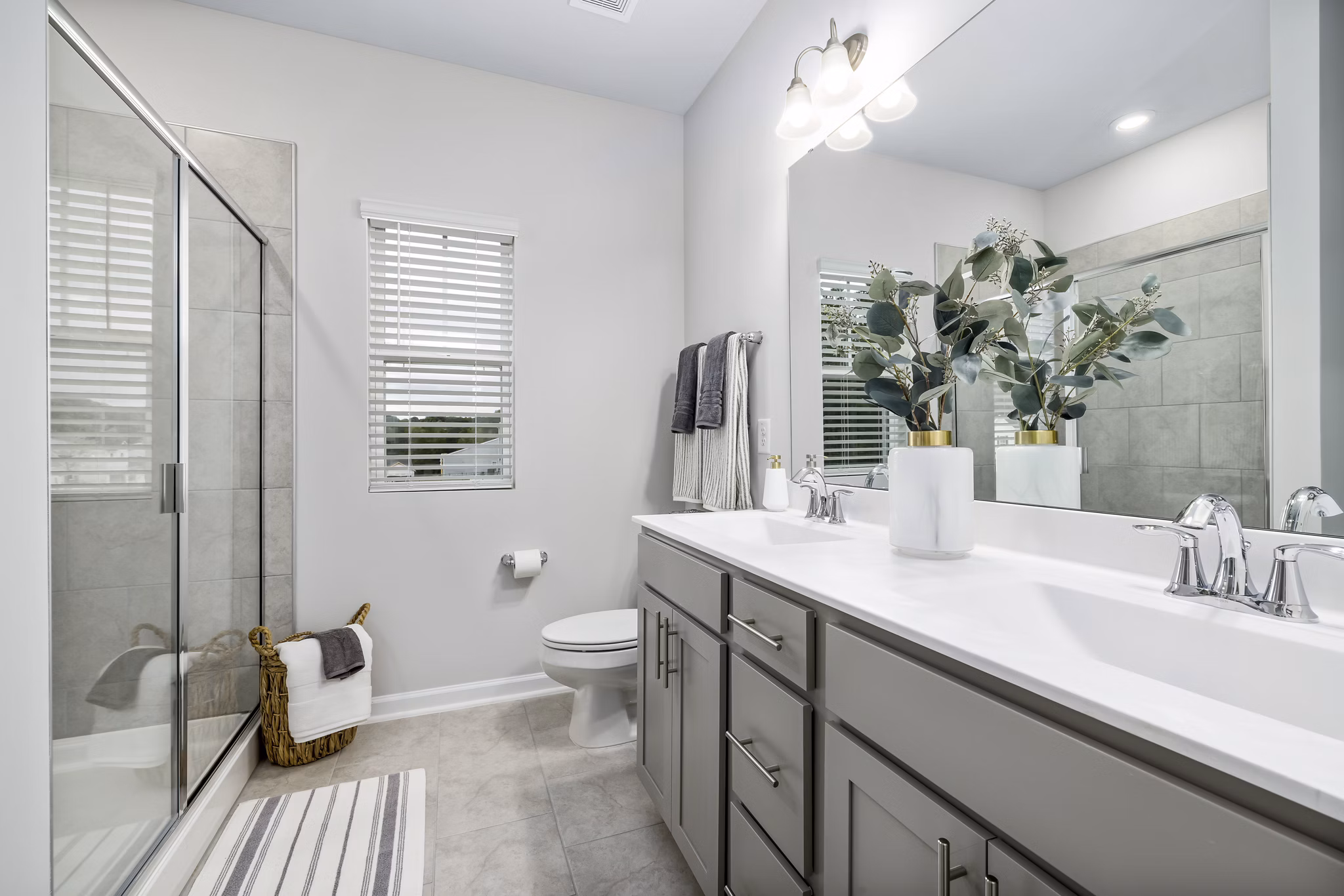 Modern bathroom with glass shower and marble countertop at Abode at Geneva Apartment Townhomes