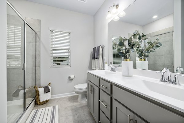 Modern bathroom with glass shower and marble countertop at Abode at Geneva Apartment Townhomes