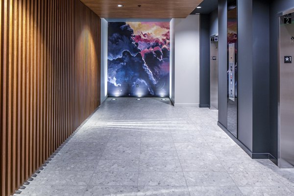 Modern hallway leading to elevators at Sawbuck Apartments, featuring sleek design for luxury living