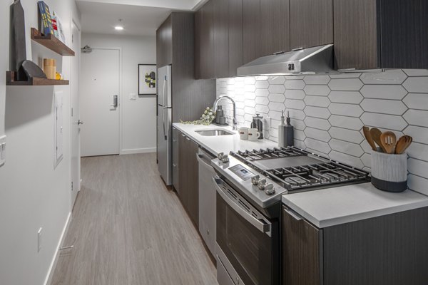 Modern kitchen with stainless steel appliances in Sawbuck Apartments