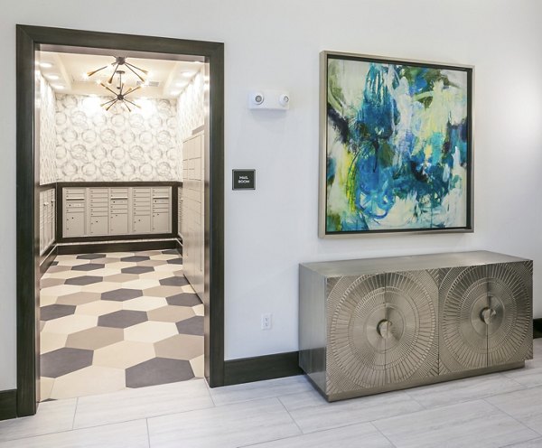Stylish hallway leading to a room with hexagonal floor tiles and a decorative console table with an abstract painting