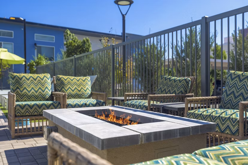 Modern luxury apartment complex with landscaped outdoor seating and blue umbrellas in the courtyard