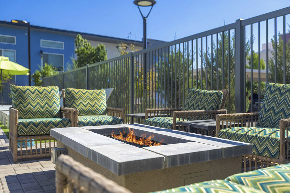 Modern luxury apartment complex with landscaped outdoor seating and blue umbrellas in the courtyard