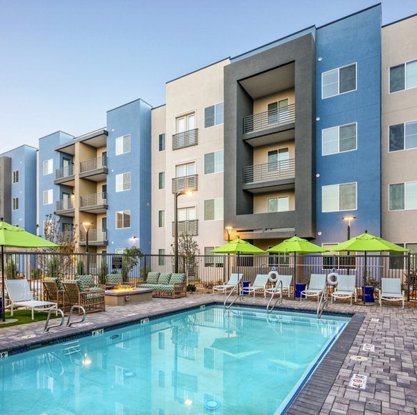 Luxury apartment complex with a swimming pool and lounge chairs in a serene outdoor setting