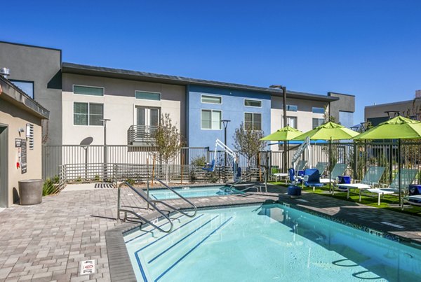 Outdoor swimming pool with lounge chairs and umbrellas at luxury apartments