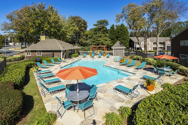 Outdoor pool with sun loungers at Trellis Apartments in tranquil garden setting