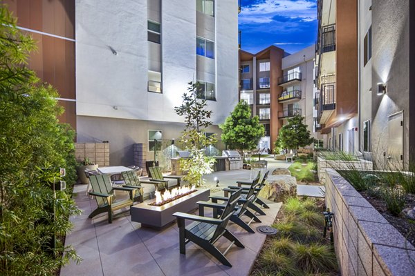 Cozy fire pit and grill area at Alexan Gallerie Apartments, ideal for social gatherings and outdoor cooking