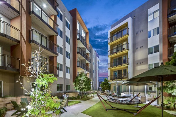 Scenic courtyard with lush greenery at Alexan Gallerie Apartments, offering a tranquil outdoor space for residents to unwind and relax