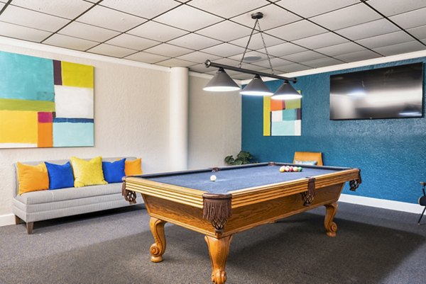 Modern clubhouse game room with pool table and plush seating at Glo Apartments, offering social space for residents
