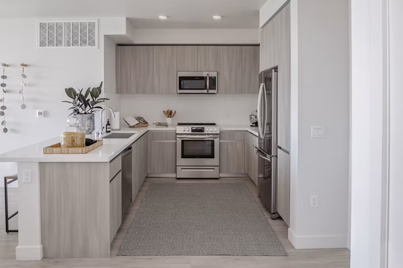 Modern kitchen with sleek countertops and stainless steel appliances at VOX Apartments in luxury property Greystar community