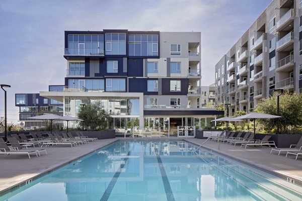 Resort-style pool with lounge chairs at VOX Apartments, offering luxurious amenities for residents