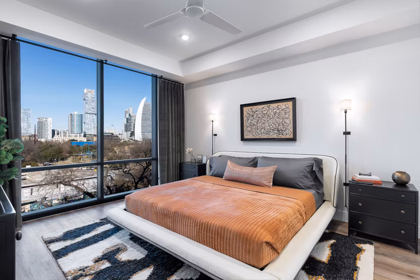 Elegant bedroom with modern decor and large windows at 1155 Barton Springs Apartments