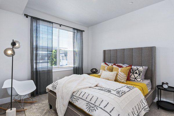Modern bedroom featuring stylish decor and large windows at The Lofts at Ten Mile Apartments