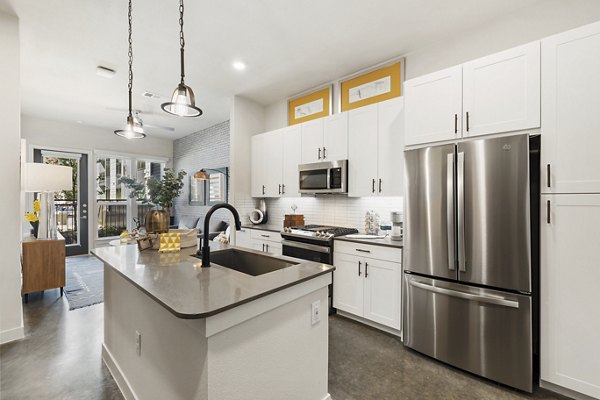Modern kitchen with stainless steel appliances and granite countertops at Art House Sawyer Yards Apartments, a luxury living space in Houston