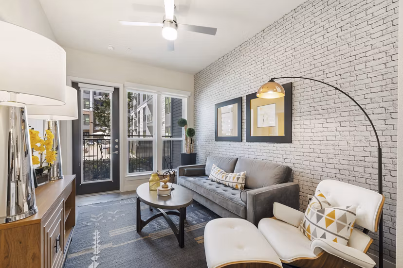 Living room with contemporary decor and large windows at Art House Sawyer Yards Apartments