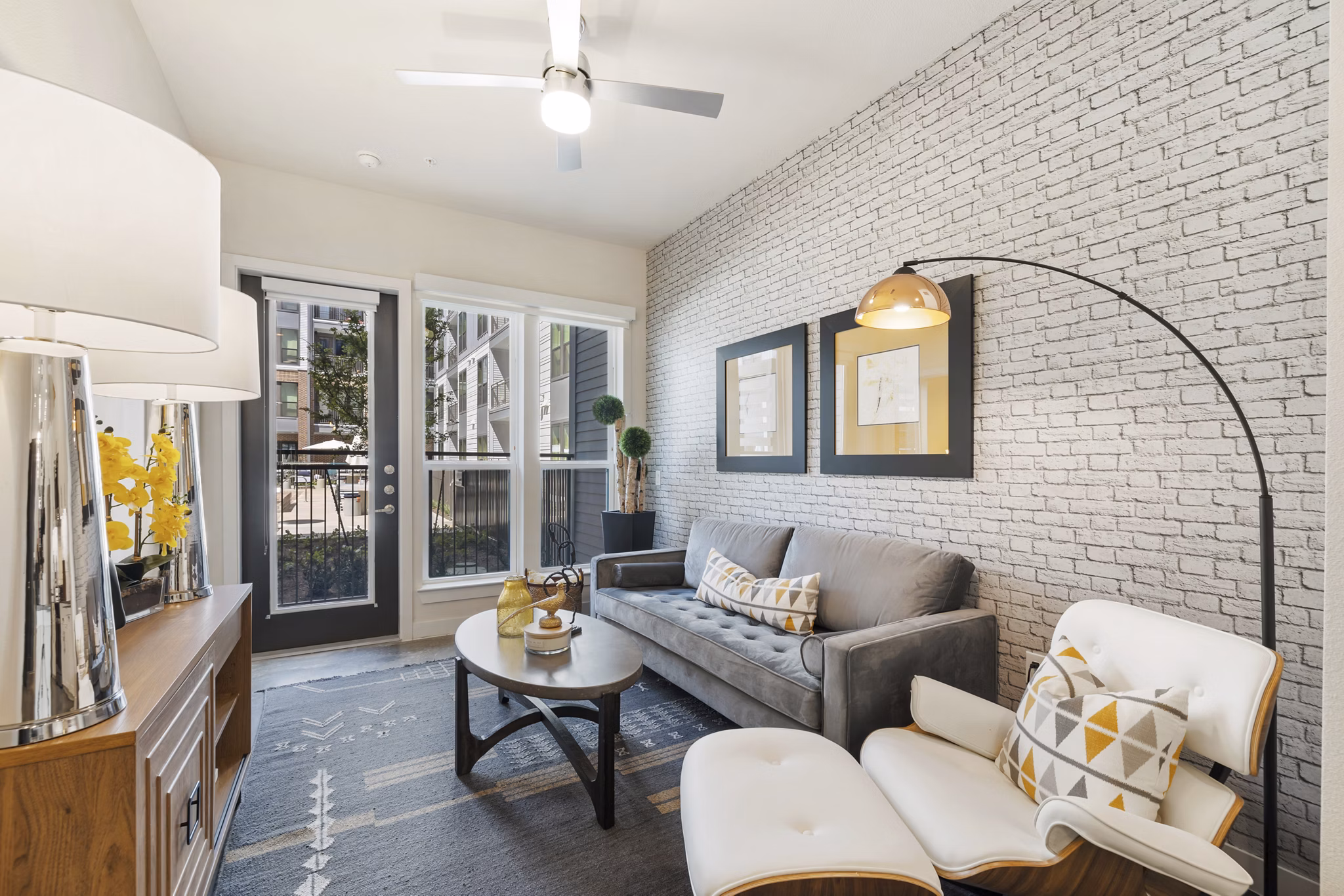 Living room with contemporary decor and large windows at Art House Sawyer Yards Apartments