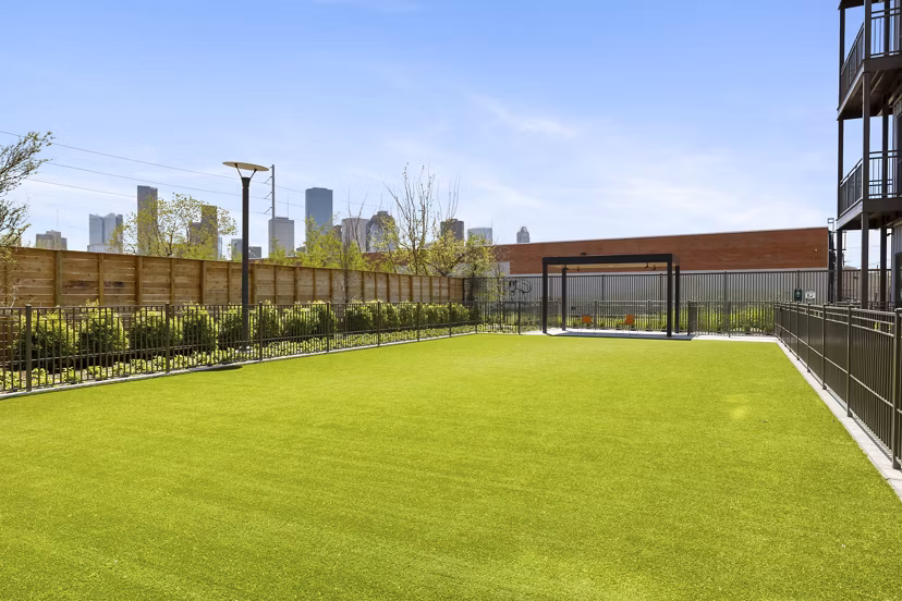 Spacious dog park equipped with agility features at Art House Sawyer Yards Apartments, providing a pet-friendly environment for residents