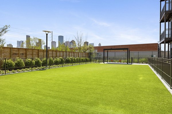 Spacious dog park equipped with agility features at Art House Sawyer Yards Apartments, providing a pet-friendly environment for residents