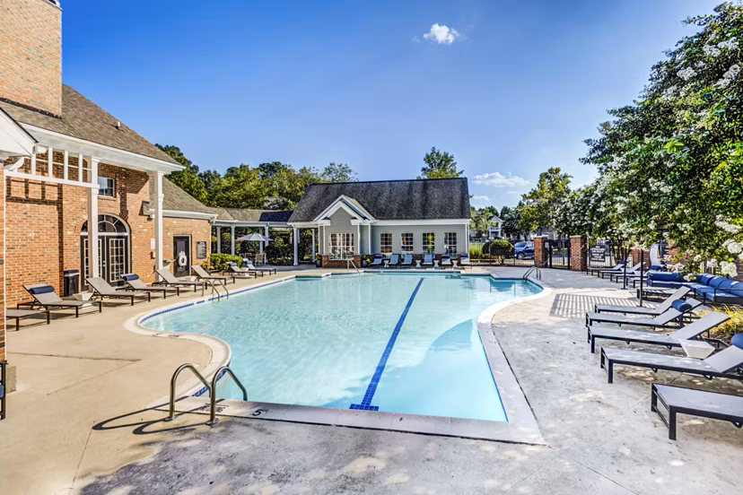 Relaxing outdoor pool at Avana on Broad Apartments with sun loungers and lush landscaping