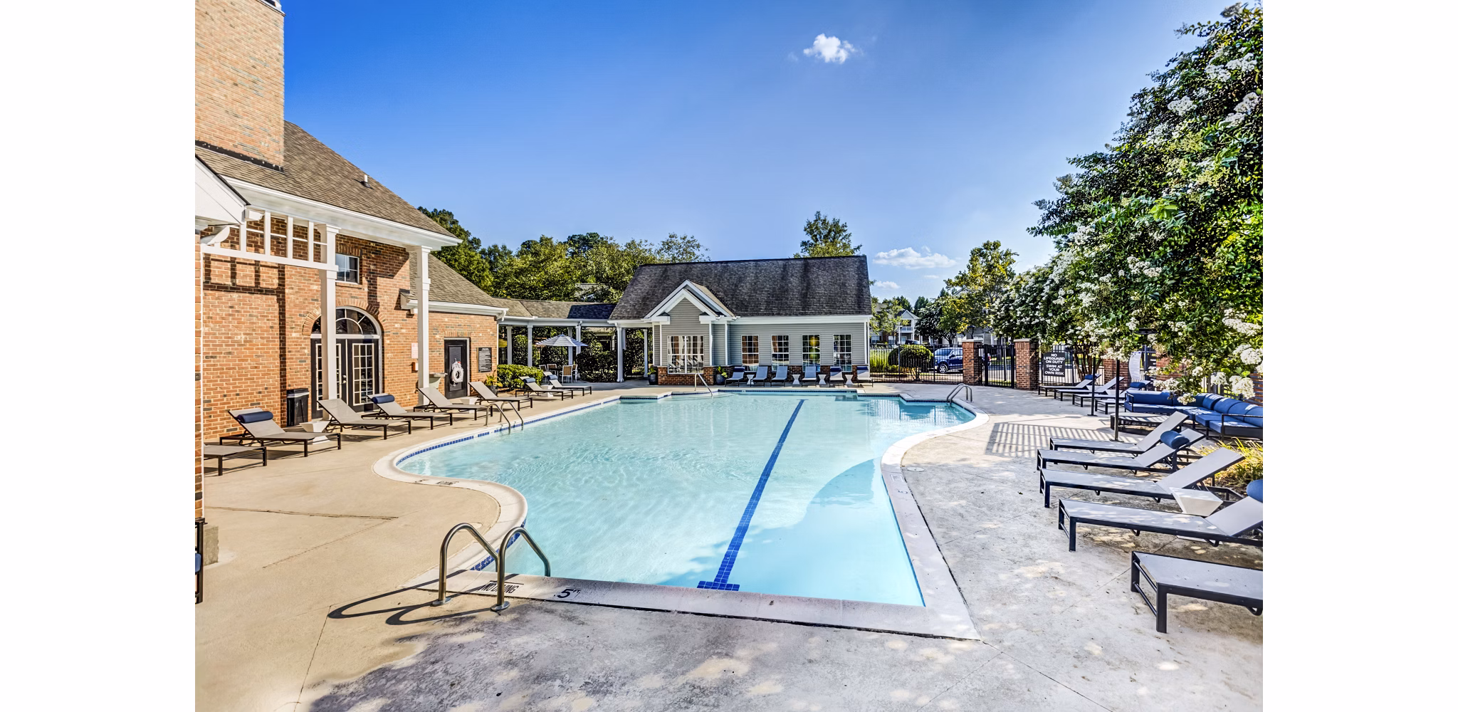 Relaxing outdoor pool at Avana on Broad Apartments with sun loungers and lush landscaping