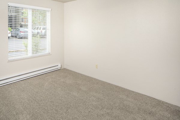 Cozy bedroom with modern decor and large window in Veri at Timberhill Apartments, luxury living in a serene setting