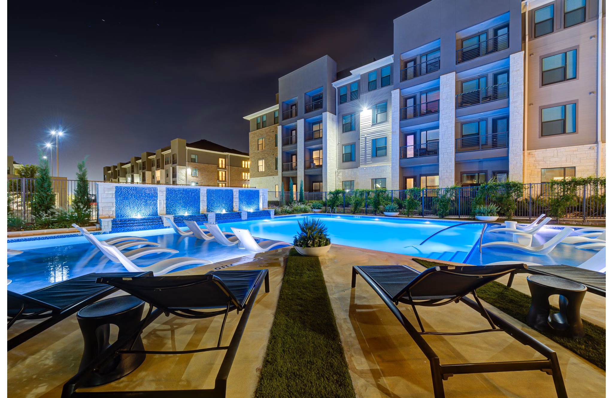 Outdoor swimming pool at The Reflection at Montgomery Ridge Apartments featuring serene surroundings and luxurious seating options