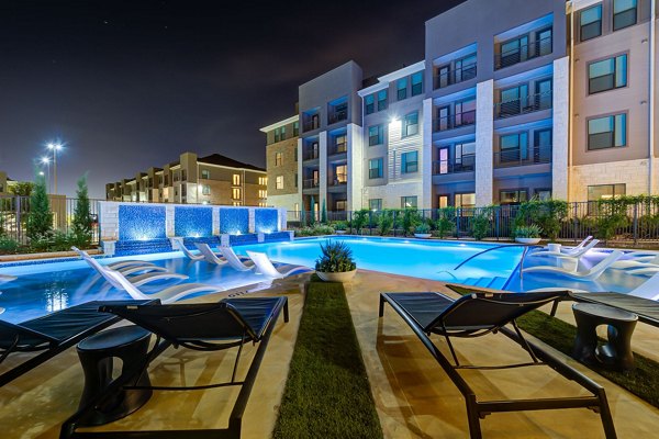 Outdoor swimming pool at The Reflection at Montgomery Ridge Apartments featuring serene surroundings and luxurious seating options