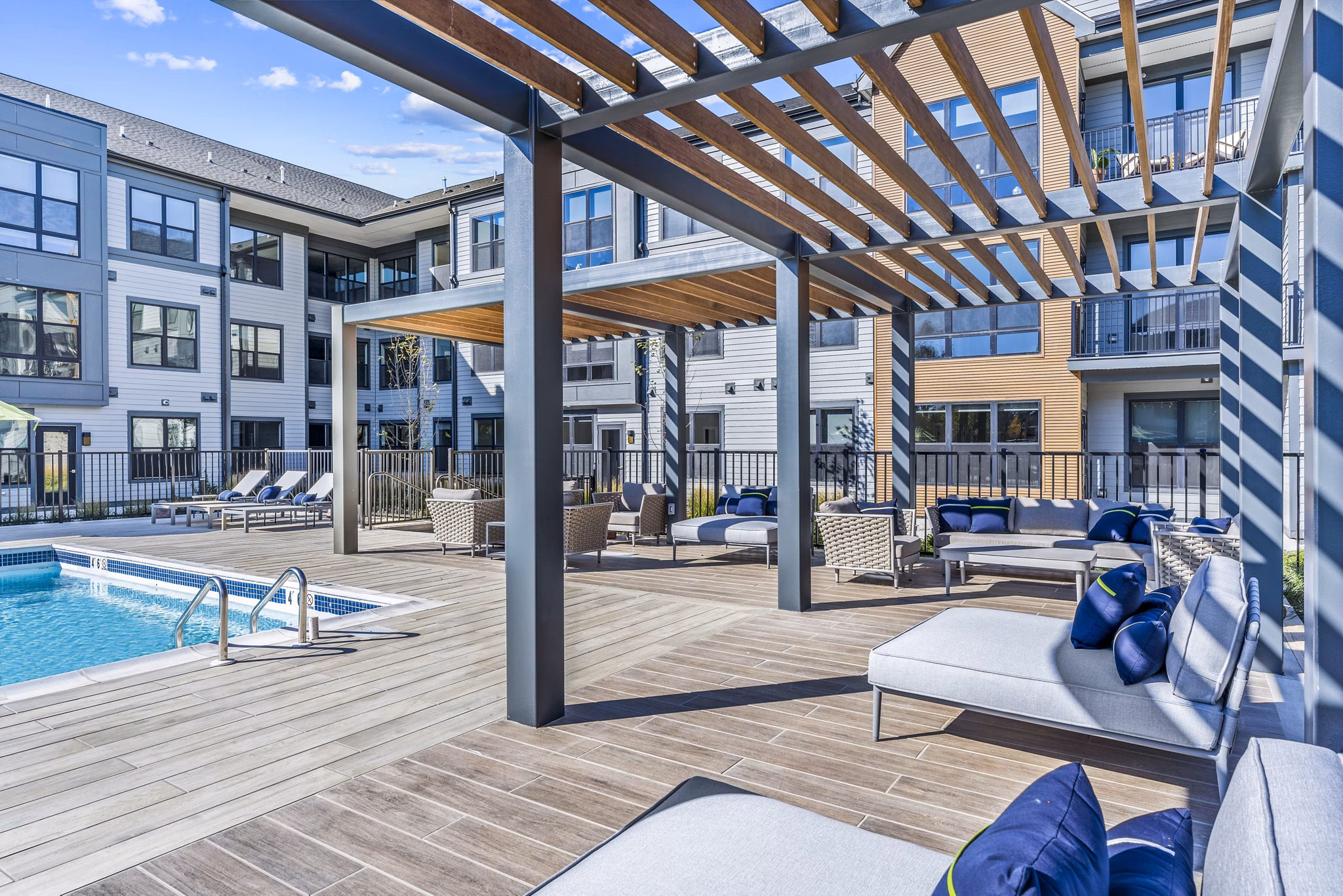 Poolside relaxation area at Canter Green Apartments with modern loungers and landscaped patio, offering a luxurious outdoor experience