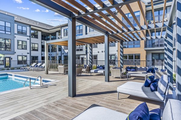 Poolside relaxation area at Canter Green Apartments with modern loungers and landscaped patio, offering a luxurious outdoor experience
