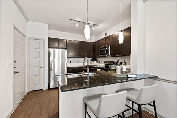 Modern kitchen with granite countertops and stainless steel appliances in Creekside Townhomes Apartments