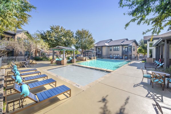 Outdoor pool area with lounge chairs at Creekside Townhomes Apartments, offering a relaxing environment for residents