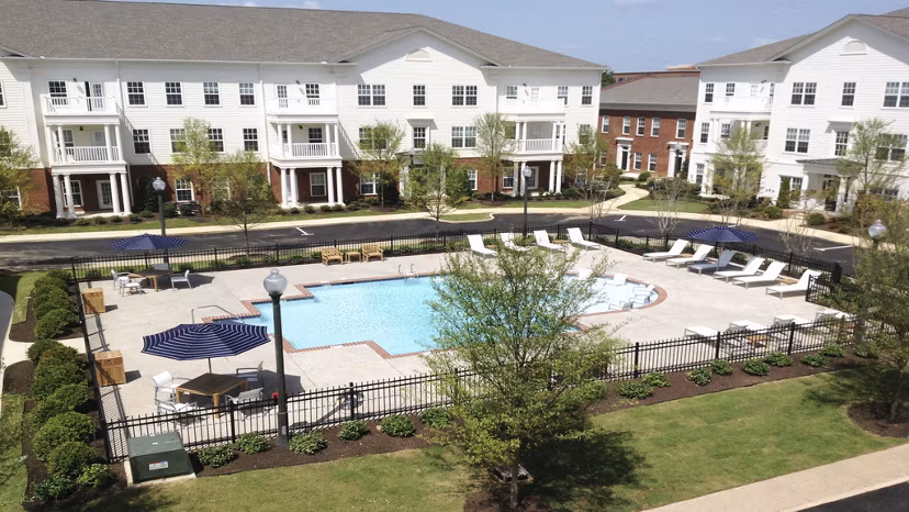 Luxury outdoor pool at Carrington at Schilling Farms Apartments with lounge chairs and lush landscaping