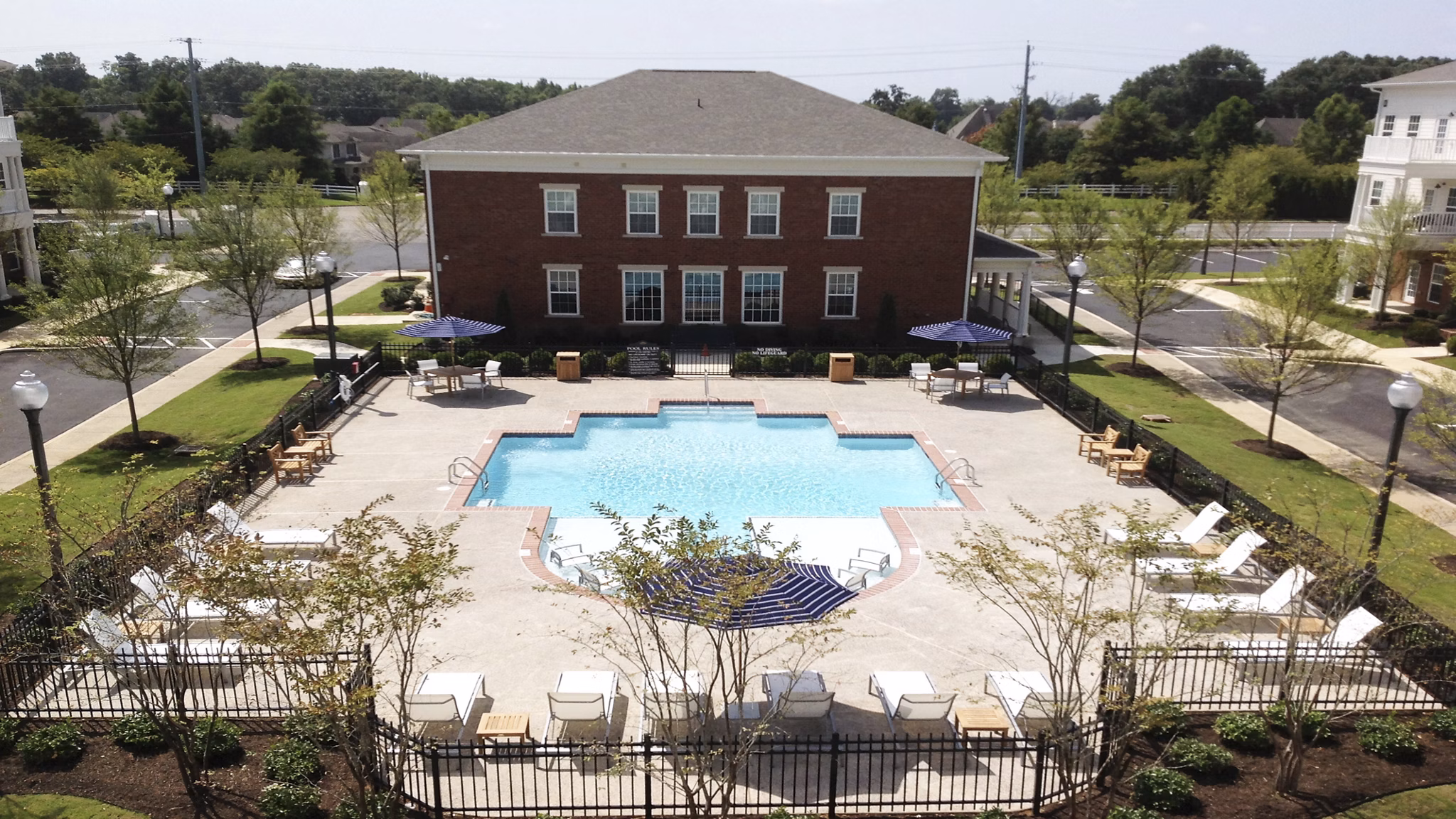 Sunlit outdoor pool at Carrington at Schilling Farms Apartments with lounge seating and lush landscaping