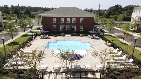Sunlit outdoor pool at Carrington at Schilling Farms Apartments with lounge seating and lush landscaping