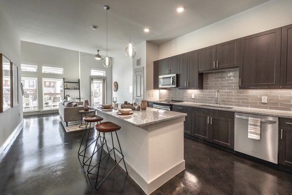 Kitchen with granite countertops and modern appliances at Alexan Flower Mound Apartments