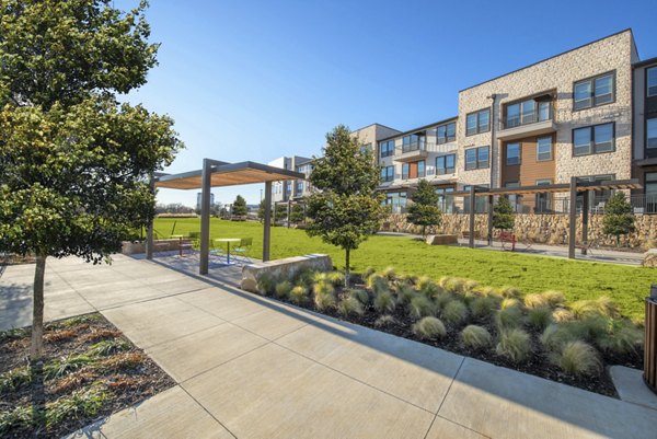 Courtyard with outdoor seating and lush greenery at Alexan Flower Mound Apartments