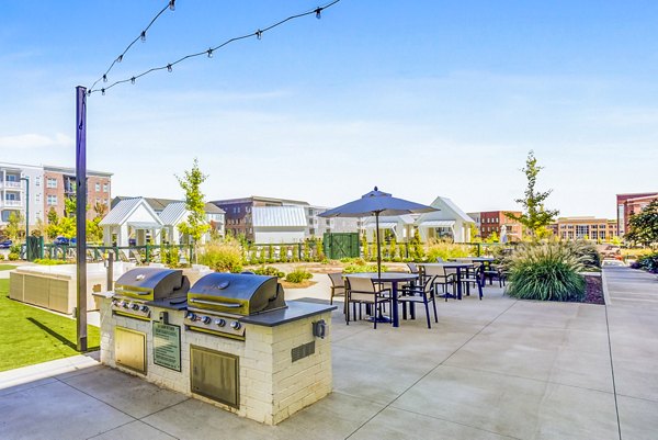 Outdoor grilling area with patio seating at Town Center at Berry Farms Apartments, ideal for social gatherings and leisure in a community-focused environment